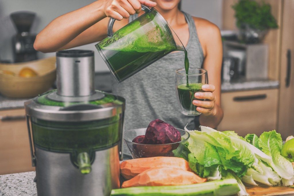 girl pouring her green juice in a glass
